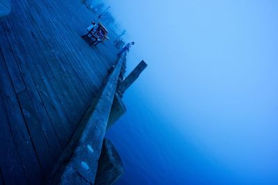 Tilt image of pier and sea against sky during foggy weather at dusk