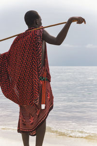 Rear view of man standing on beach against sky