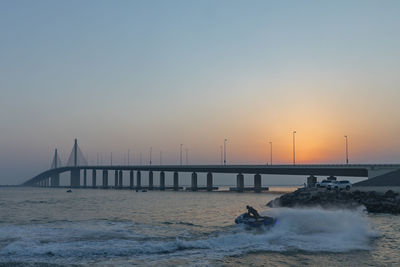 Man riding jet boat in sea against clear sky during sunset