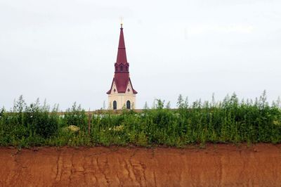 Tower on field by building against sky