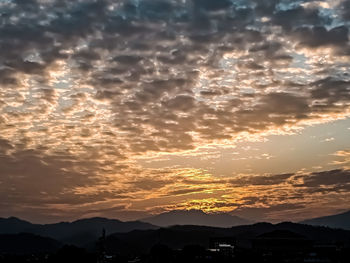 Scenic view of silhouette mountains against dramatic sky during sunset