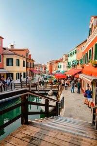 Tourist central street of burano with canal, bridges and tourists