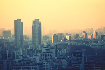 Modern buildings in city against sky during sunset