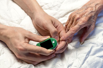 Midsection of woman holding hands on bed