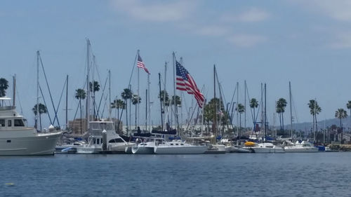 Boats moored at harbor against sky