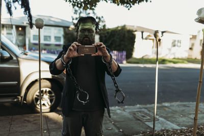 Father dressed as frankenstein holding phone during trick-or-treat