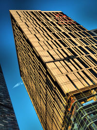 Low angle view of office building against blue sky on city