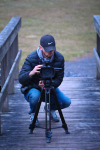 Man photographing while sitting on seat