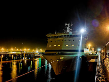 Illuminated harbor against clear sky at night