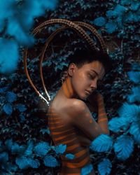 Digital composite image of shirtless woman against plants at night