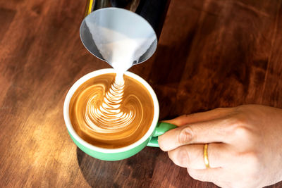 Midsection of person holding coffee cup on table