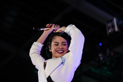 Smiling woman performing on stage at night
