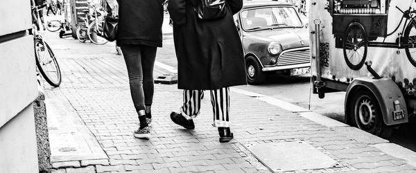 Low section of women walking on footpath in city