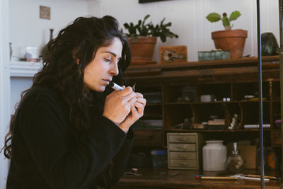 Profile portrait of female artist working on tiny jewlery in studio