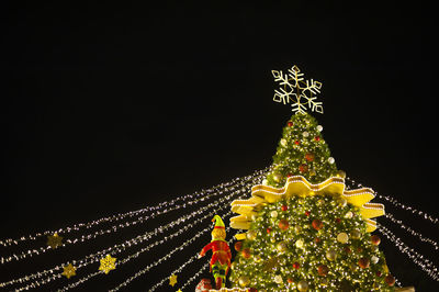 Low angle view of illuminated christmas tree against clear sky