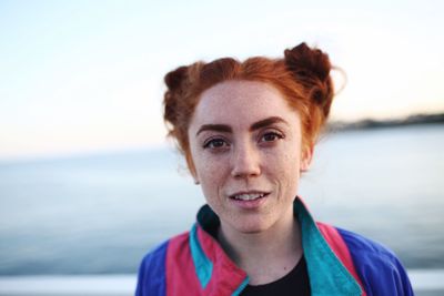 Portrait of smiling young woman against sea