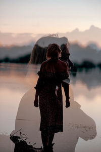 Rear view of woman standing at beach against sky during sunset