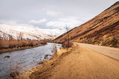 Road amidst snow covered mountain against sky