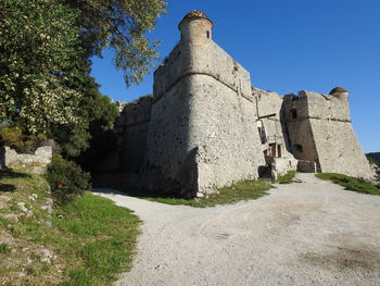 Low angle view of historic building against blue sky château fort du mont boron nice