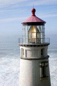 Lighthouse by sea against sky