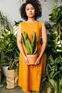 Portrait of a young woman standing against plants