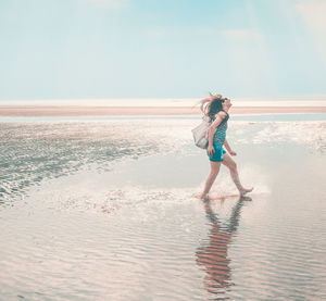 Full length of woman on beach against sky