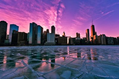 Modern buildings by swimming pool against sky during sunset