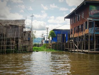 Buildings by river against sky