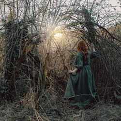 Rear view of woman standing in forest