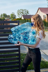 Girl holding bottles standing outdoors