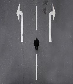 High angle view of man standing by arrow symbols on road