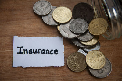 Insurance text on torn paper with jar, coins, and wooden table background. insurance concept