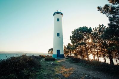 Lighthouse by sea against sky