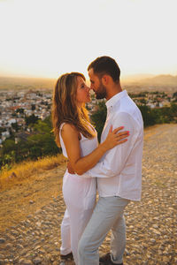 Young couple looking each other face to face while standing in city at sunset
