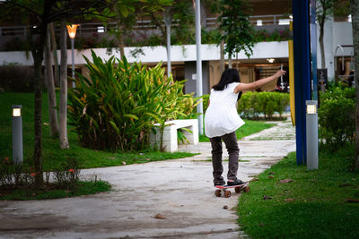 Young girl skateboarding in the park. view from behind.