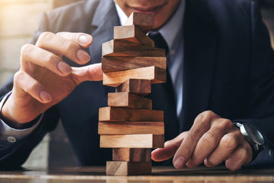 Midsection of businessman stacking wooden blocks on table