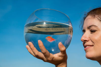 Close-up of woman holding crystal ball against sky