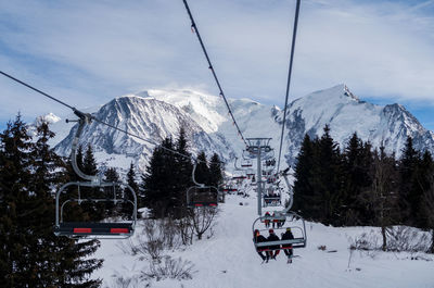 Ski lift over snowcapped mountains against sky