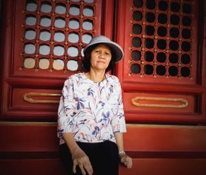 Portrait of smiling young woman standing against red wall