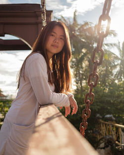 Portrait of smiling young woman standing on swing