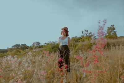 Full length of woman standing on field against sky