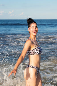 Portrait of woman in bikini standing at beach