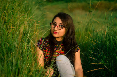 Portrait of young woman sitting on field