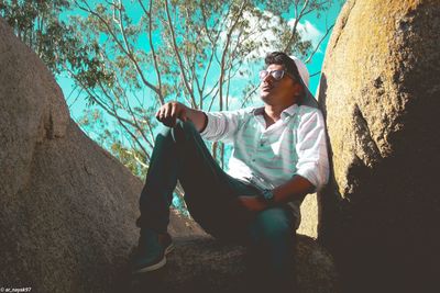 Young man sitting on rock