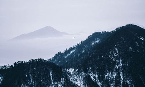 Idyllic shot of mountains in foggy weather against sky