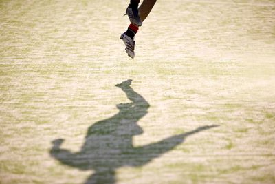 Low section of soccer player jumping over field on sunny day