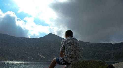 Rear view of man looking at mountains against sky