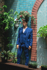 A man in a blue suit close his eyes under the pink flowers headpiece