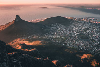 Aerial view of cityscape by sea at sunset