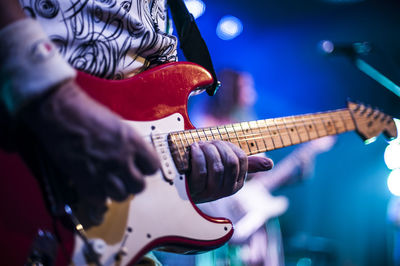 Midsection of guitarist performing at concert